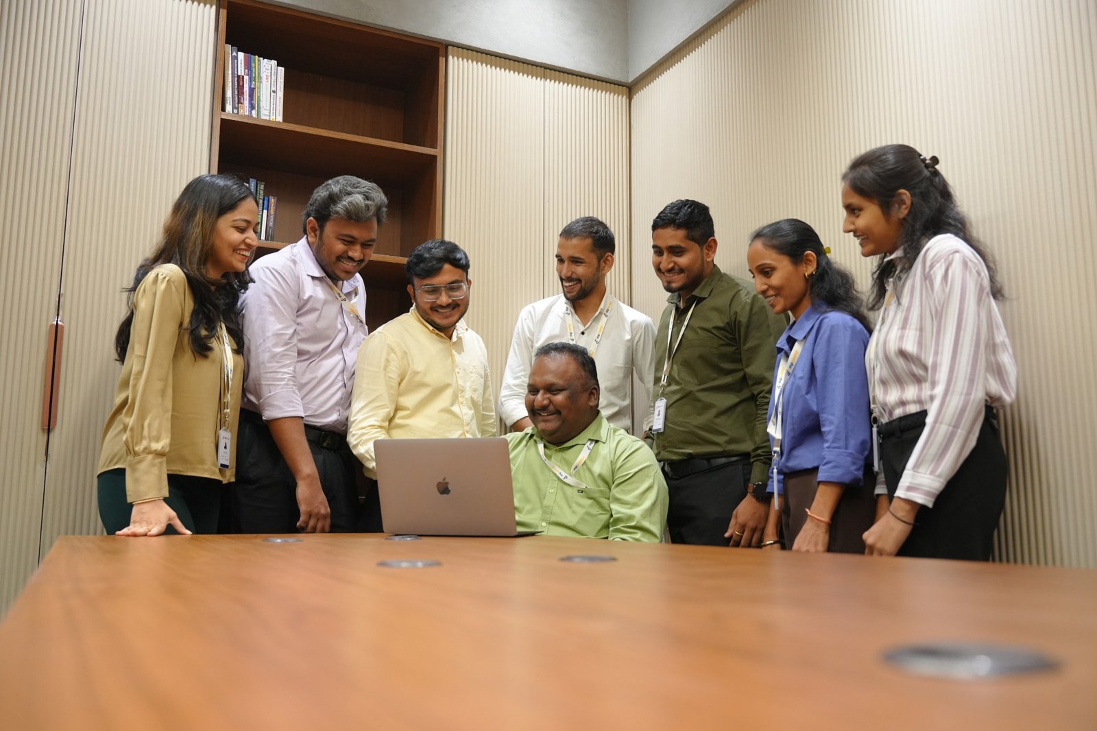 Colleagues gathered around a laptop in a meeting room